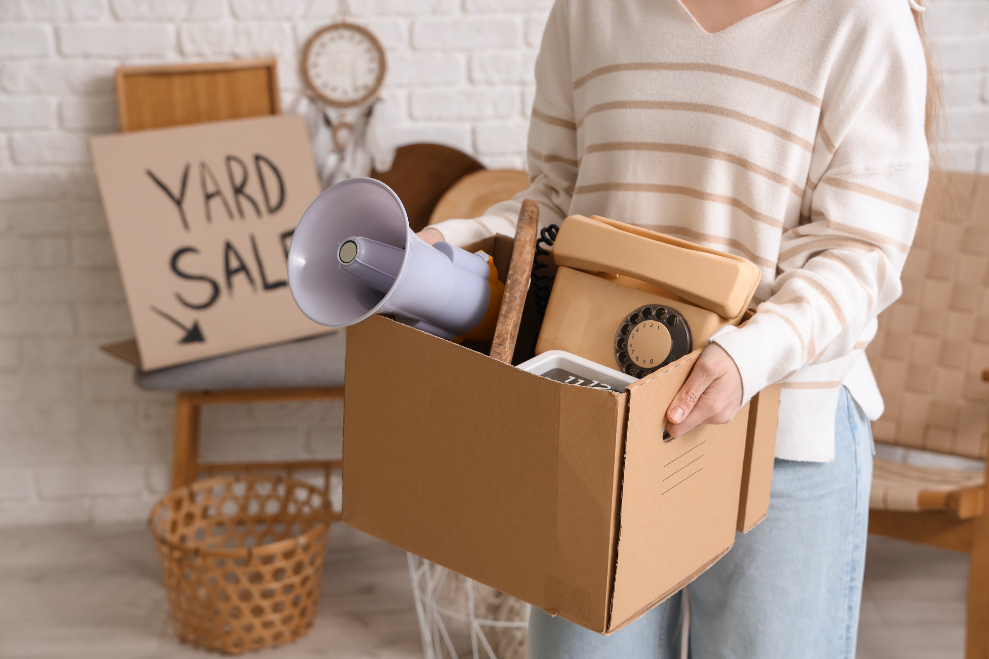 Woman Holding Box of Unwanted Stuff for Yard Sale in Room