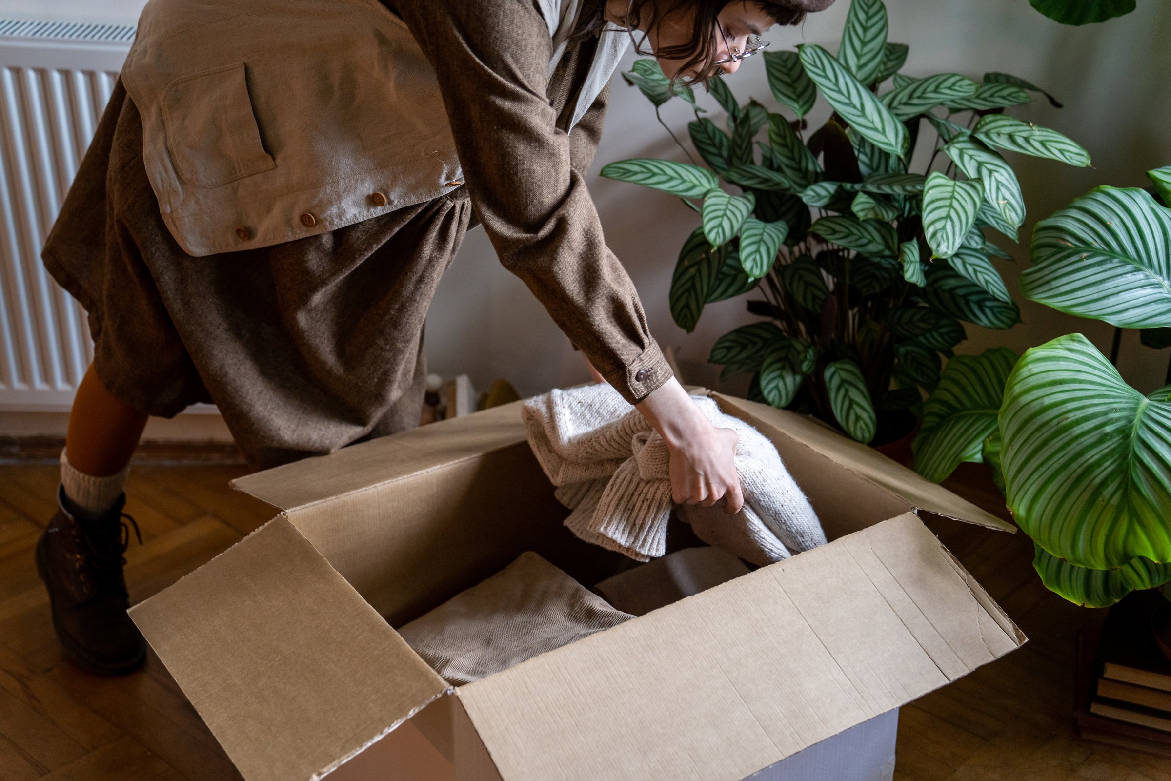 Woman Sorting Clothes at Home, Putting Clothing Items in Cardboard Box